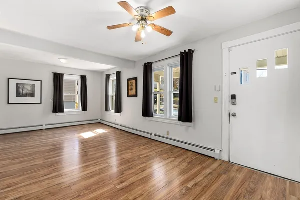 a view of an empty room with window and wooden floor