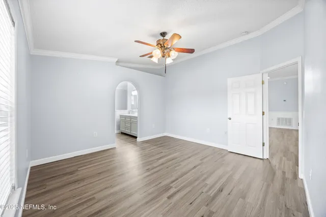 an empty room with wooden floor chandelier fan and windows