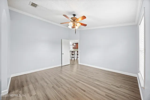a view of an empty room with window and wooden floor