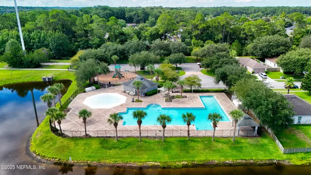 a view of a swimming pool with a yard and large trees