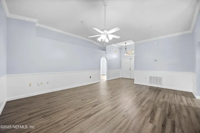 an empty room with wooden floor and a ceiling fan