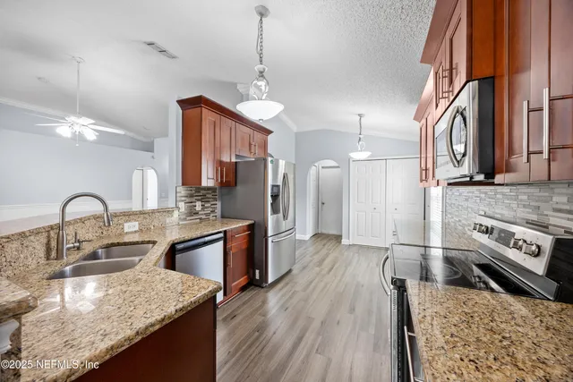 a kitchen with stainless steel appliances granite countertop a sink a stove and a wooden floors