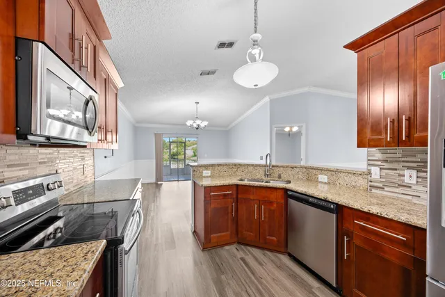 a large kitchen with stainless steel appliances granite countertop a lot of counter space and wooden floor