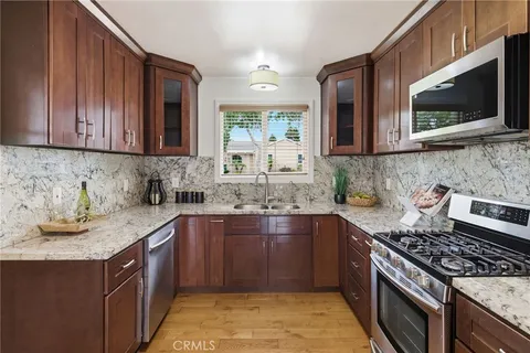 a kitchen with stainless steel appliances granite countertop wooden cabinets a stove top oven a sink and dishwasher