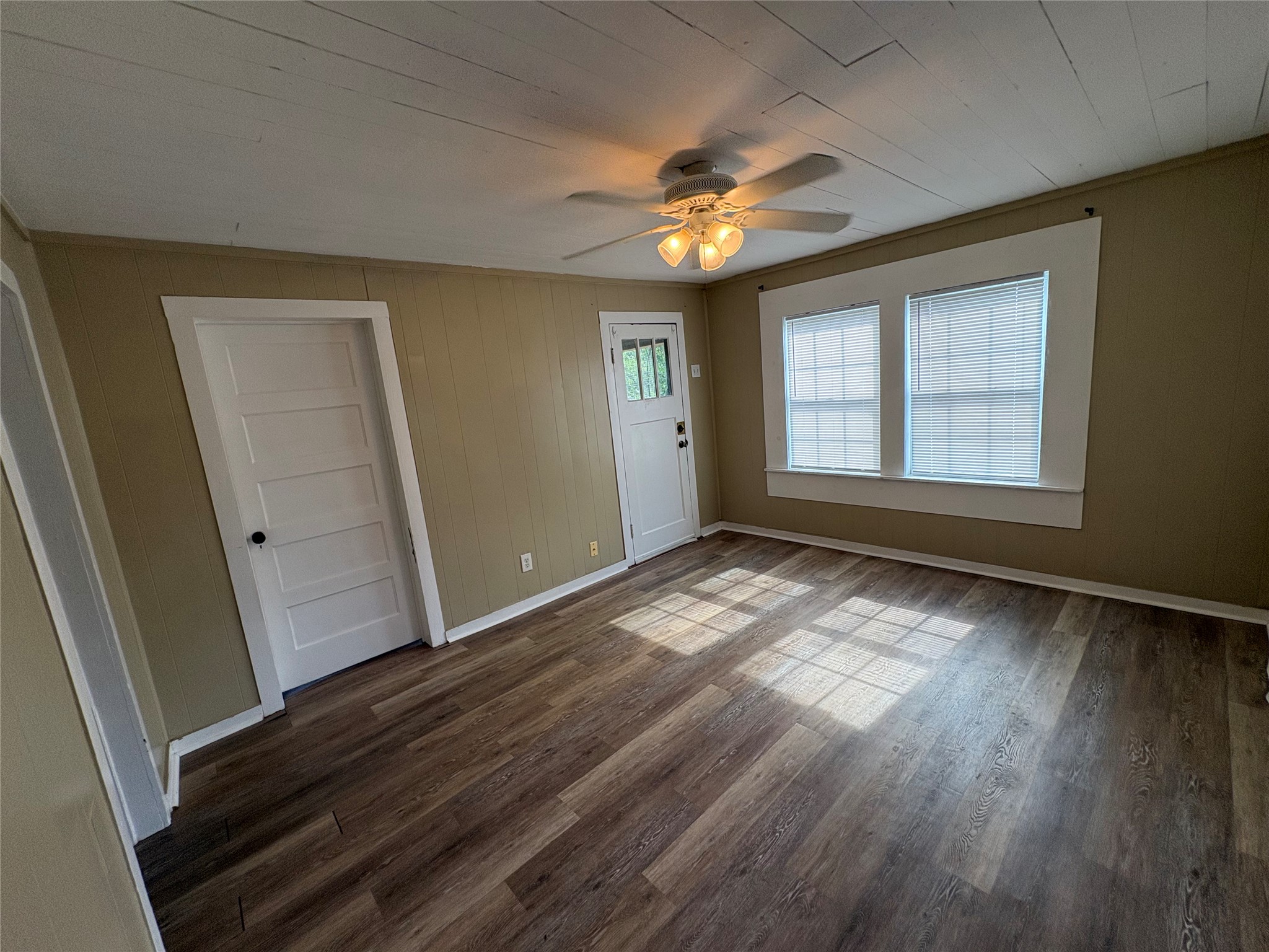 2305 Main Street Bastrop, TX 78602 - Photo 3 of 11 Newly installed wood-look flooring enhances this versatile living area, illuminated by natural light and a central ceiling fan.