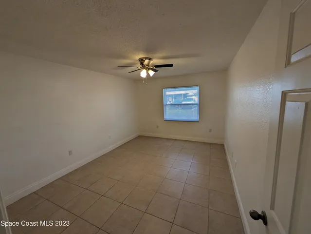 an empty room with windows and fan