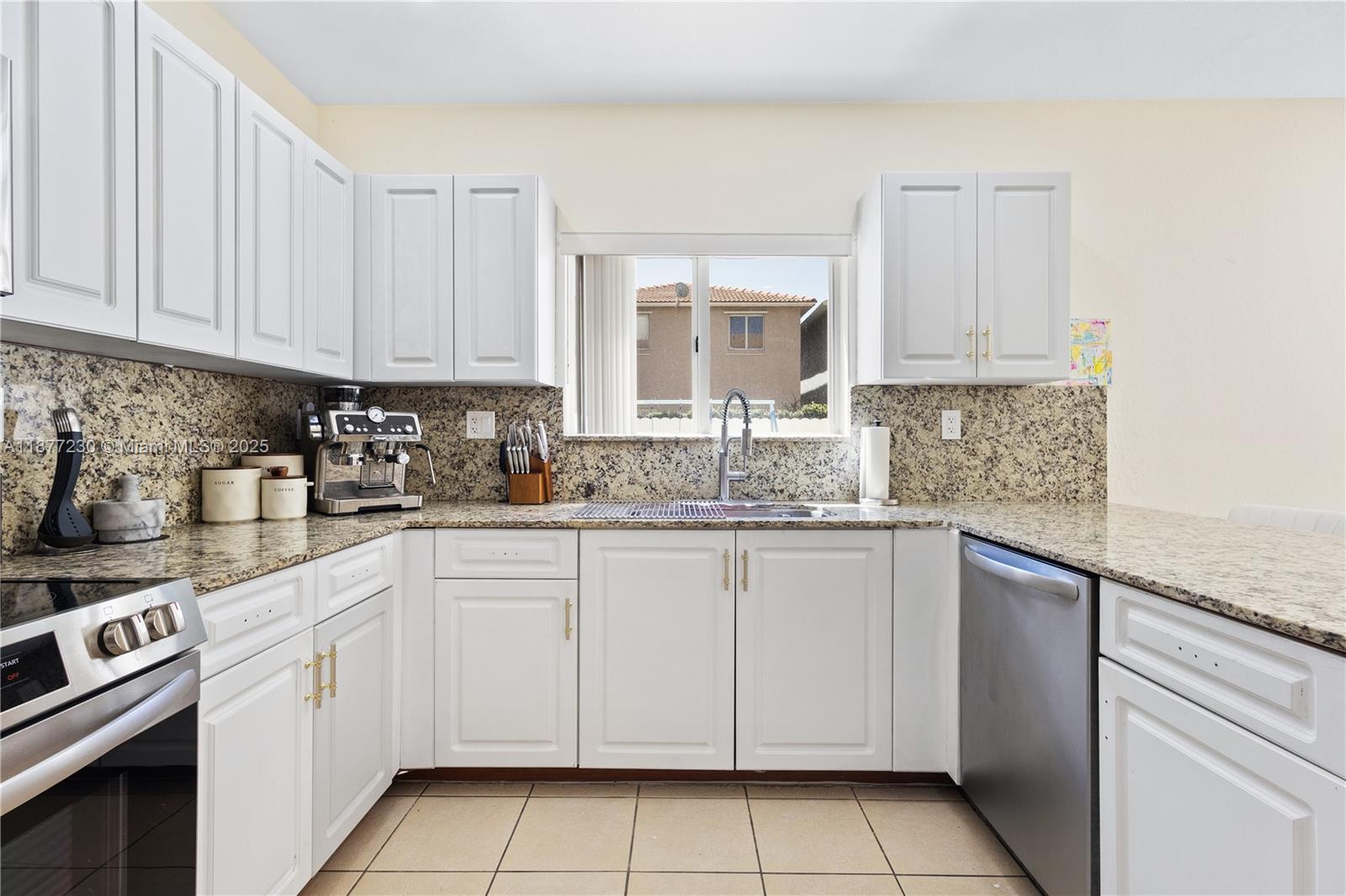 16256 Southwest 57th Lane Miami, FL 33193 - Photo 12 of 32 a kitchen with granite countertop white cabinets and white appliances
