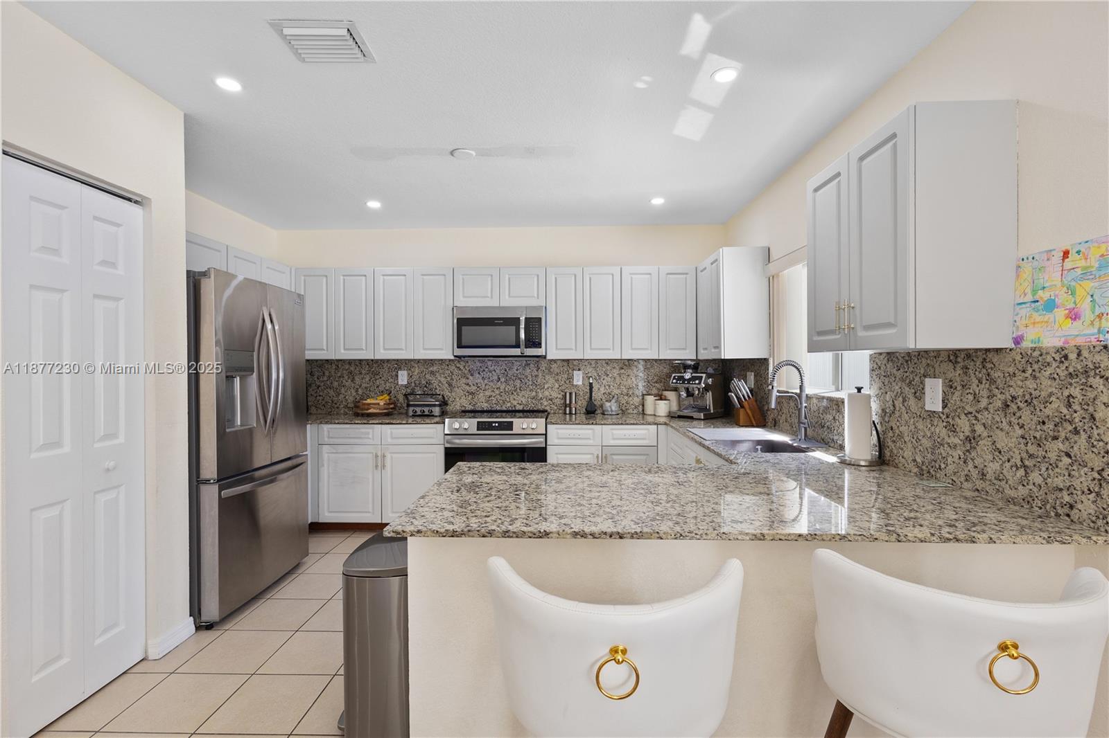 16256 Southwest 57th Lane Miami, FL 33193 - Photo 13 of 32 a kitchen with a refrigerator a sink a stove a microwave and cabinets