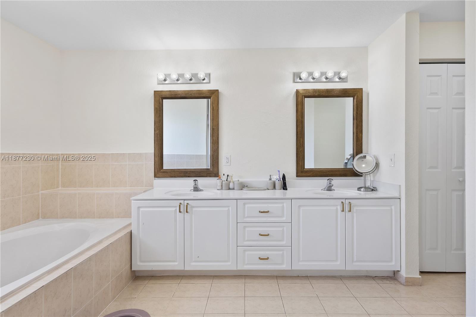 16256 Southwest 57th Lane Miami, FL 33193 - Photo 22 of 32 a bathroom with a double vanity sink a mirror and a bathtub