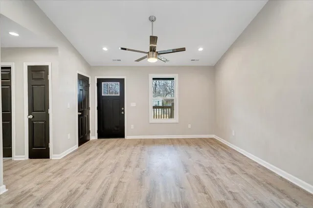 an empty room with wooden floor and windows