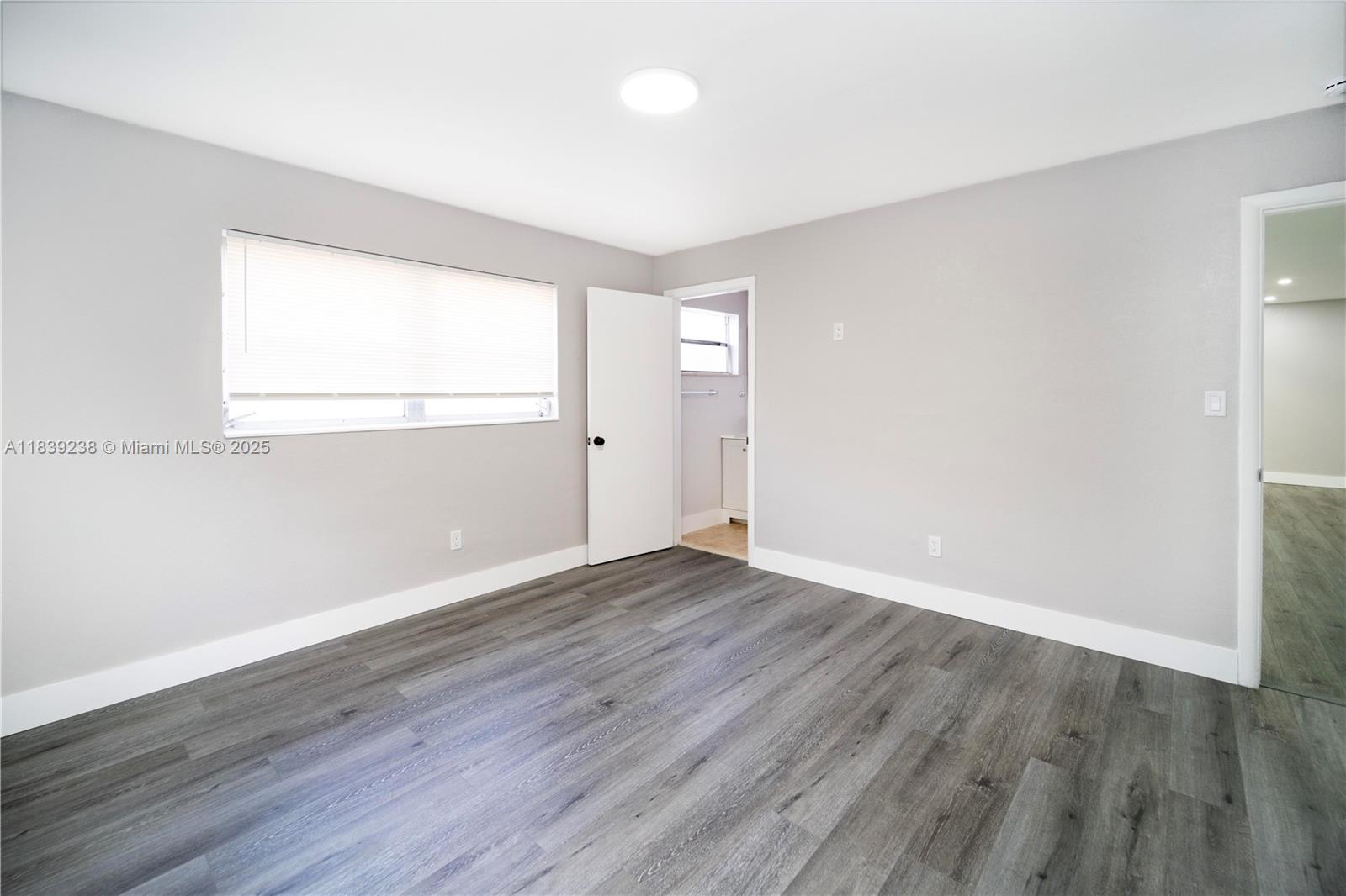 6990 Southwest 28th Street Miramar, FL 33023 - Photo 13 of 33 an empty room with wooden floor and windows