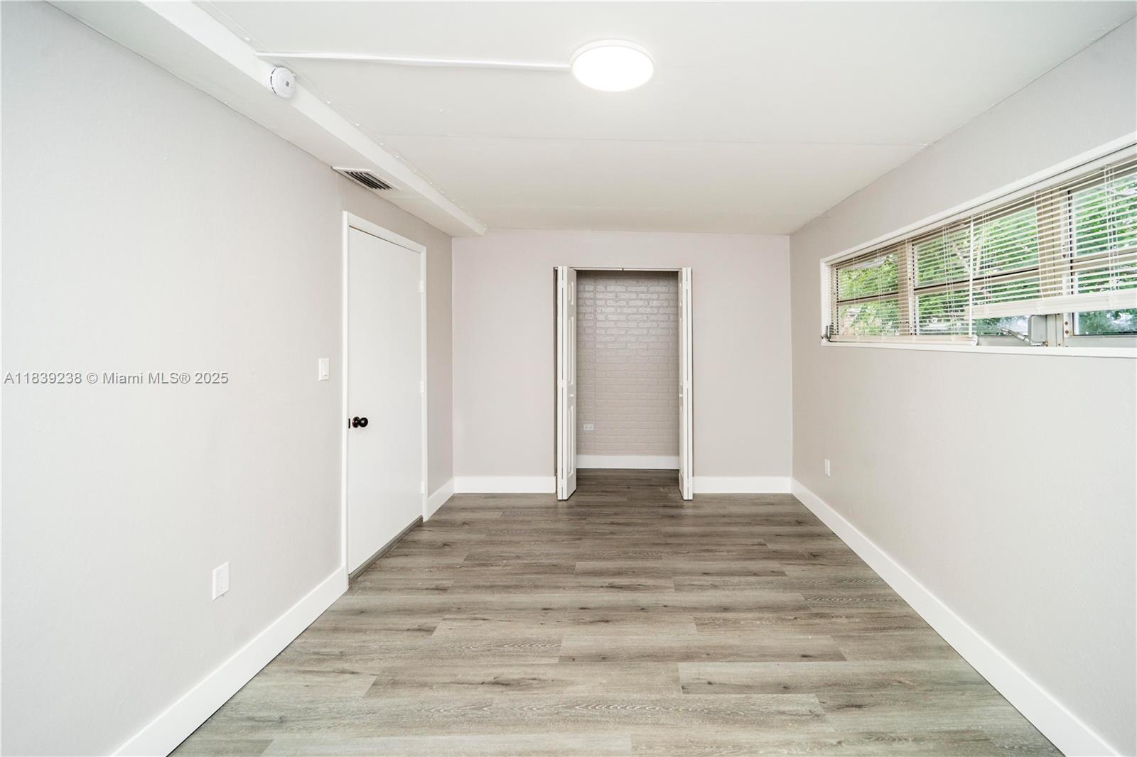 6990 Southwest 28th Street Miramar, FL 33023 - Photo 18 of 33 a view of an empty room with wooden floor and a window