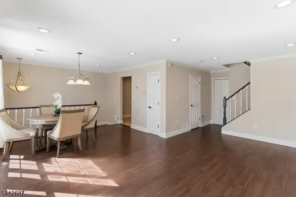 a dining room with wooden floor a chandelier a glass table and chairs