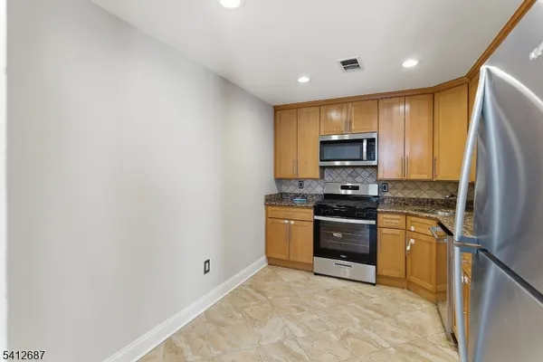 a kitchen with stainless steel appliances granite countertop a refrigerator a stove top oven a sink and dishwasher