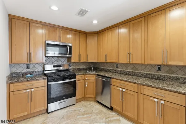 a kitchen with stainless steel appliances granite countertop a stove a sink and a microwave