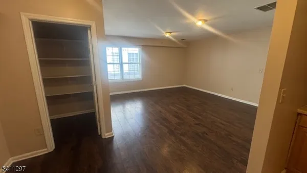 a view of an empty room with a window and wooden floor