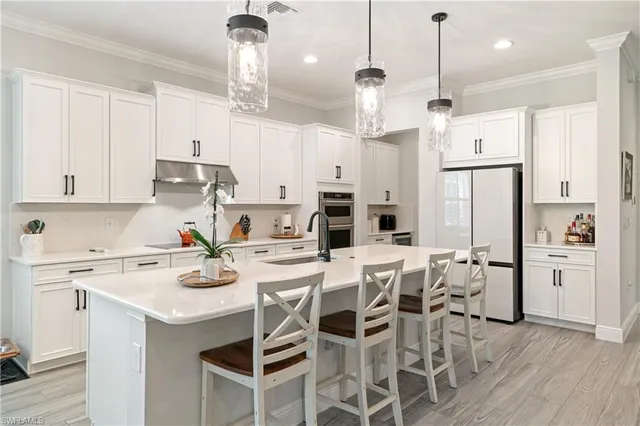 a kitchen with stainless steel appliances kitchen island a refrigerator and white cabinets
