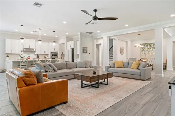a living room with furniture kitchen view and a wooden floor