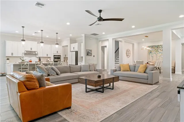 a living room with furniture kitchen view and a wooden floor