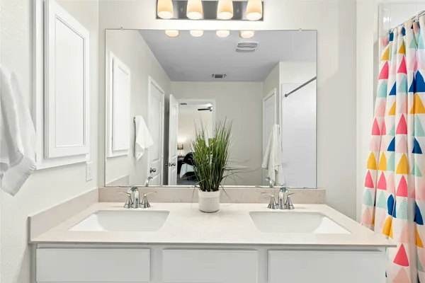 a bathroom with a double vanity sink mirror and bathtub