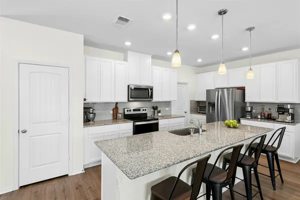 a kitchen with refrigerator a stove and a wooden floor