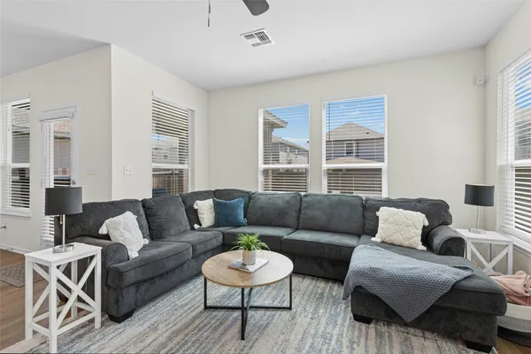 a living room with stainless steel appliances kitchen island granite countertop a dining table chairs and couches with wooden floor