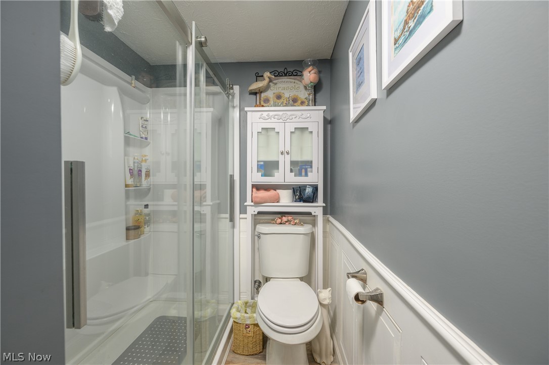 390 Ross Road Waynesburg, OH 44688 - Photo 26 of 30 Full bathroom featuring a wainscoted wall, a shower stall, a decorative wall, and a textured ceiling