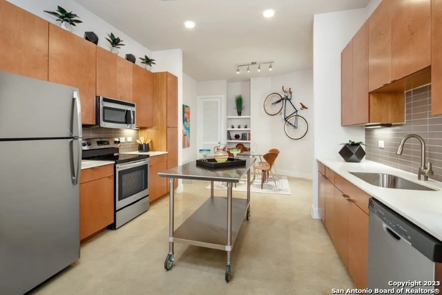 a kitchen with granite countertop stainless steel appliances a sink and a refrigerator