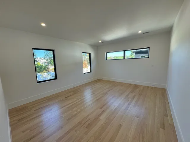 a view of an empty room with wooden floor and a window