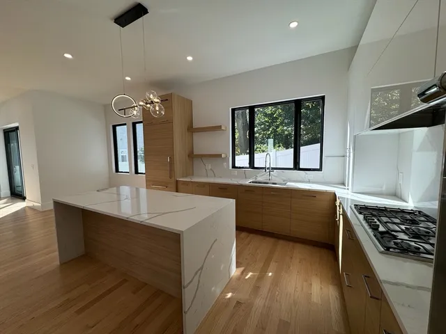 a large kitchen with stainless steel appliances a large counter top a stove and a sink