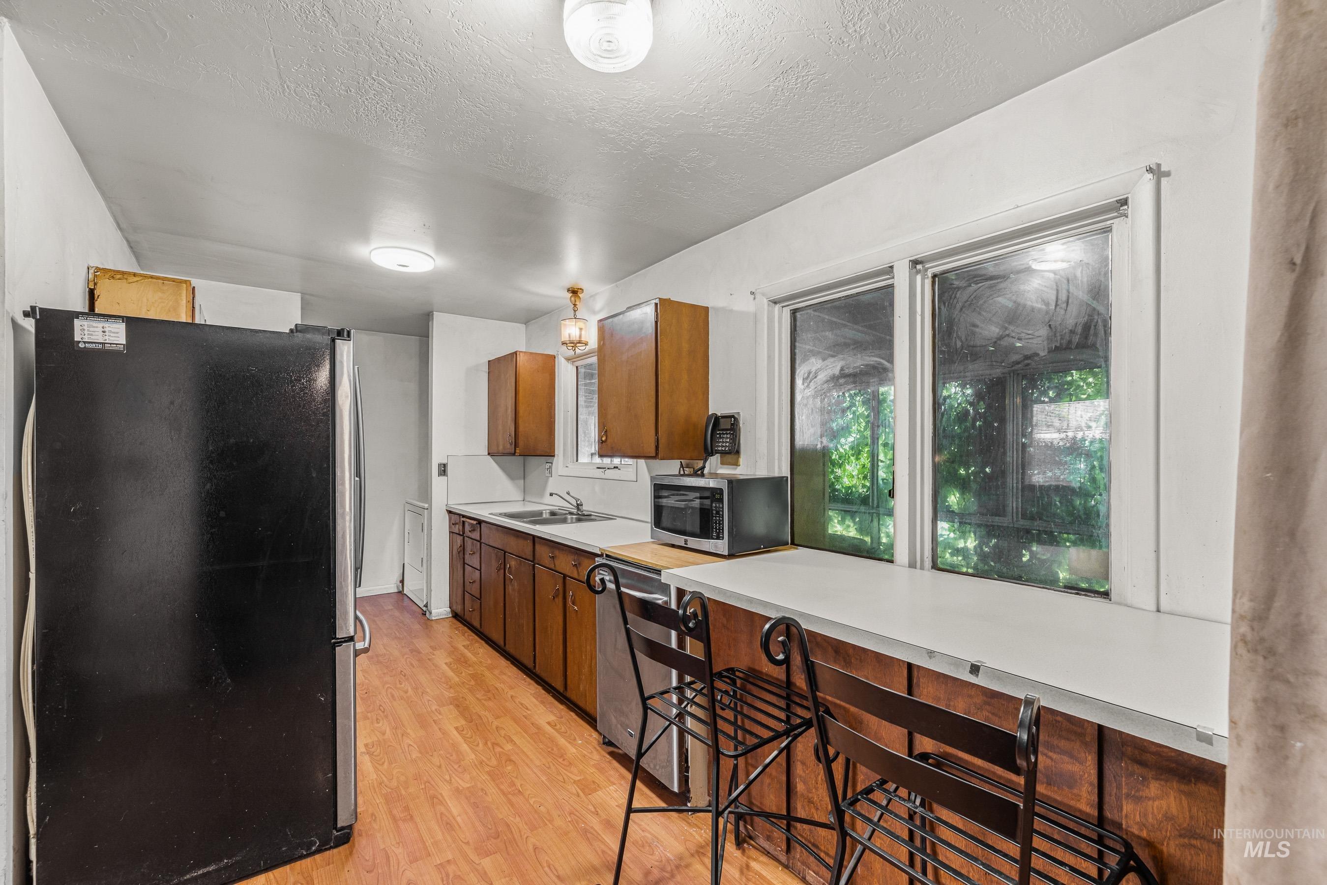 7026 S Highway Riggins, ID 83549 - Photo 25 of 50 Kitchen with wood-finish flooring, wood cabinetry, built-in stainless steel sink, dual pane windows, and a breakfast bar