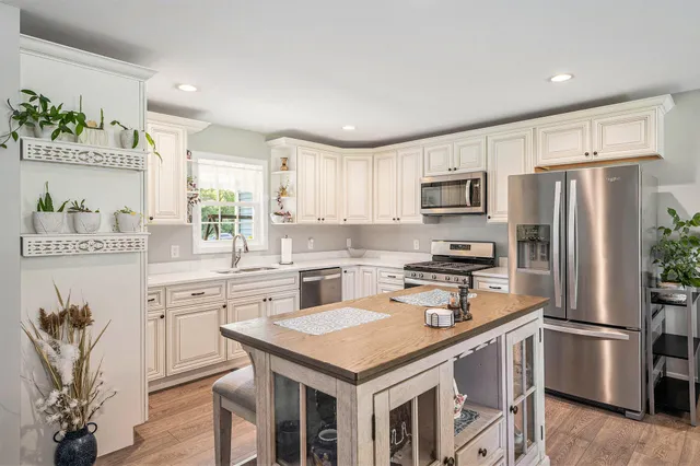 a kitchen with a refrigerator a stove a sink dishwasher and white cabinets with wooden floor