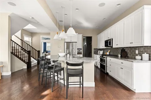 a kitchen with stainless steel appliances kitchen island granite countertop a stove a sink a dining table and chairs with wooden floor