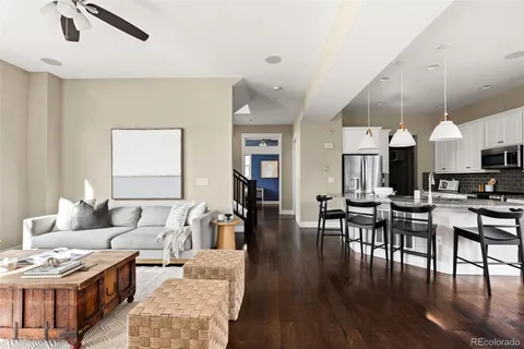 a living room with furniture kitchen view and a wooden floor