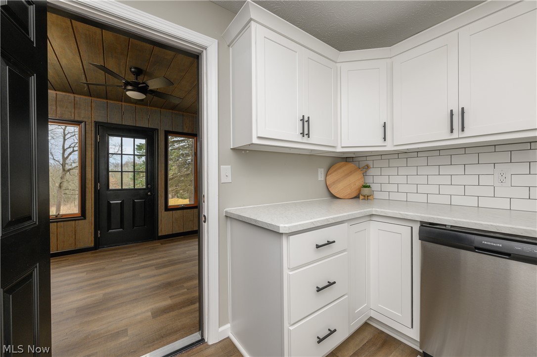 6484 Manchester Road Clinton, OH 44216 - Photo 11 of 21 Kitchen with ceiling fan, stainless steel dishwasher, light wood-type flooring, backsplash, and white cabinetry