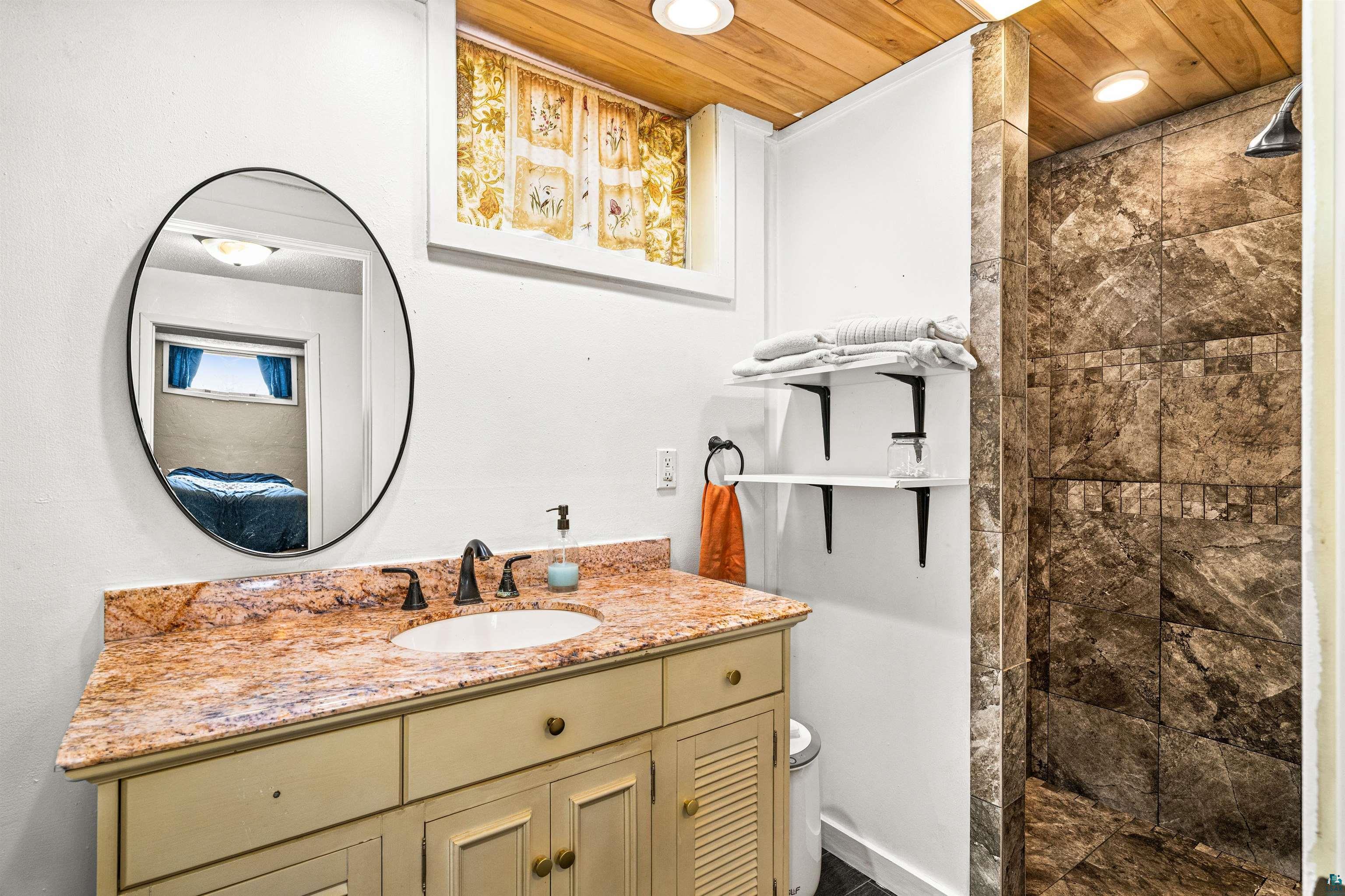 3325 Strand Road Duluth, MN 55803 - Photo 21 of 25 Full bathroom featuring a vanity with a granite countertop, undermount sink, and dark bronze faucet.