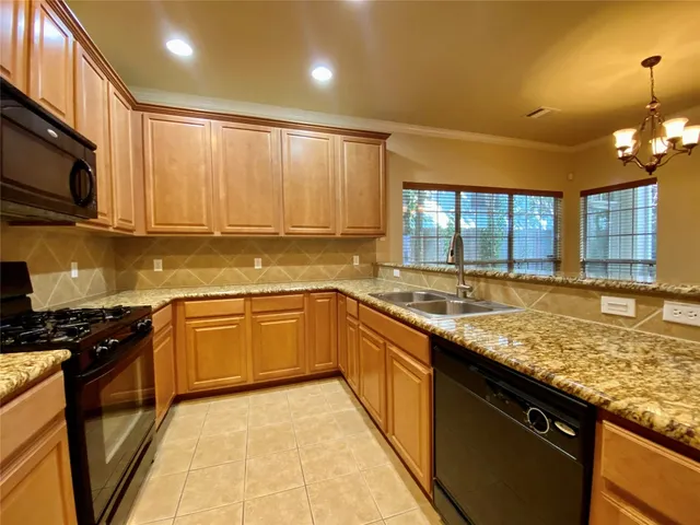 a large kitchen with granite countertop a stove sink and cabinets