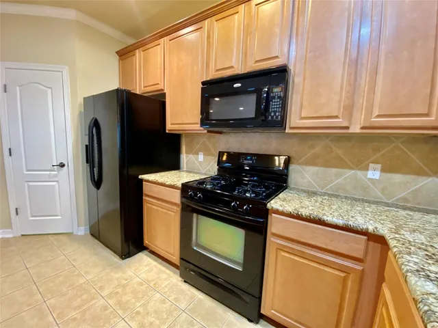 a kitchen with stainless steel appliances granite countertop a stove a refrigerator and a microwave