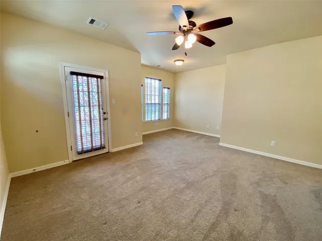 an empty room with windows and fan