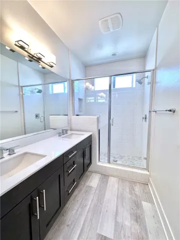 a spacious bathroom with a double vanity sink a large mirror and shower