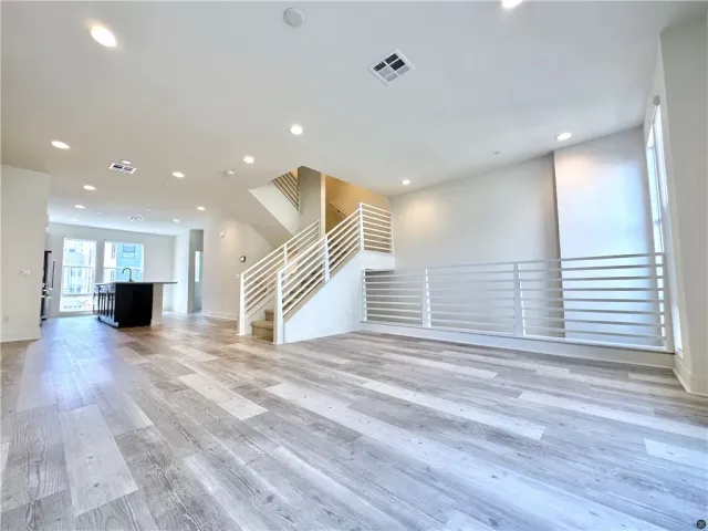 a view of an empty room with wooden floor and stairs