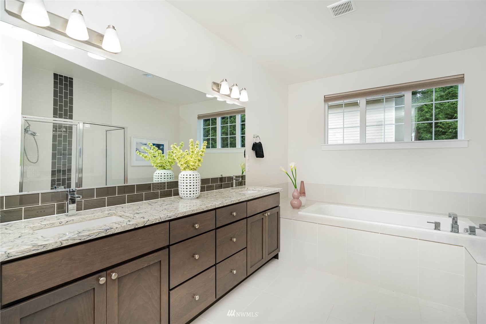 10133 Northeast 147th Street Bothell, WA 98011 - Photo 17 of 39 a bathroom with a granite countertop double vanity sink a large mirror a bathtub and next to a window