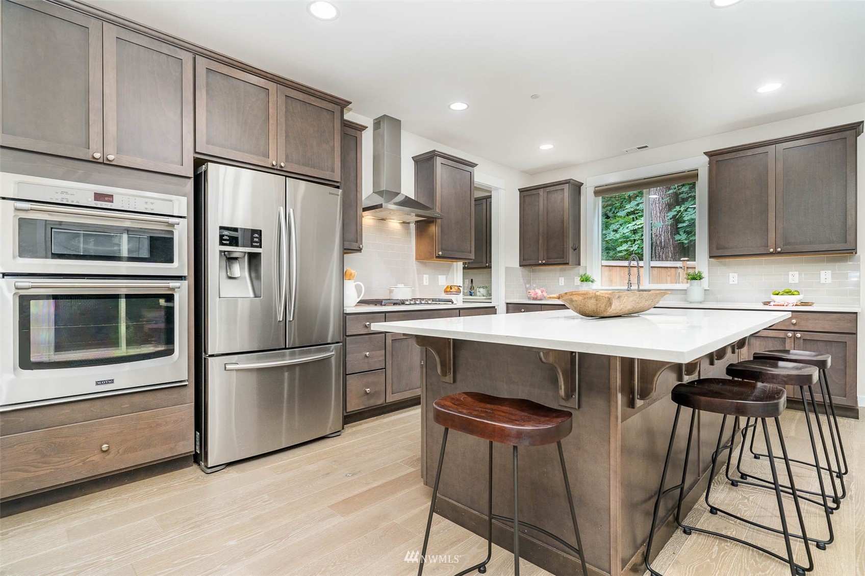 10133 Northeast 147th Street Bothell, WA 98011 - Photo 7 of 39 a kitchen with a refrigerator a sink and a stove top oven with wooden floor