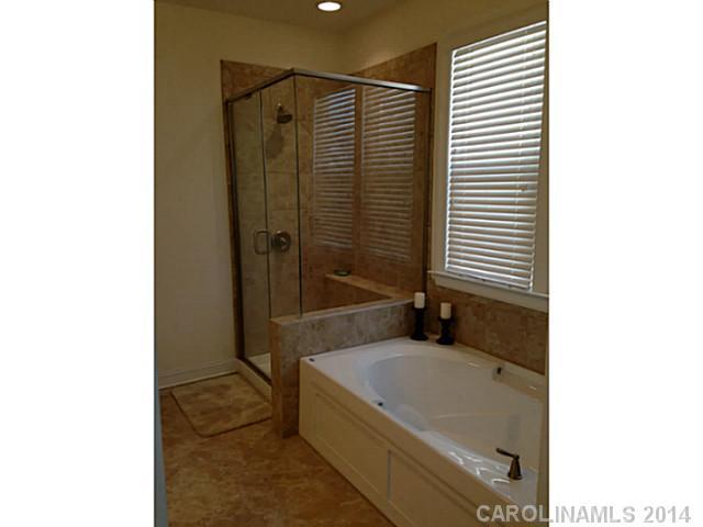 5000 Fallondale Road, Unit 885 Waxhaw, NC 28173 - Photo 11 of 16 a bathroom with a granite countertop bathtub shower and sink