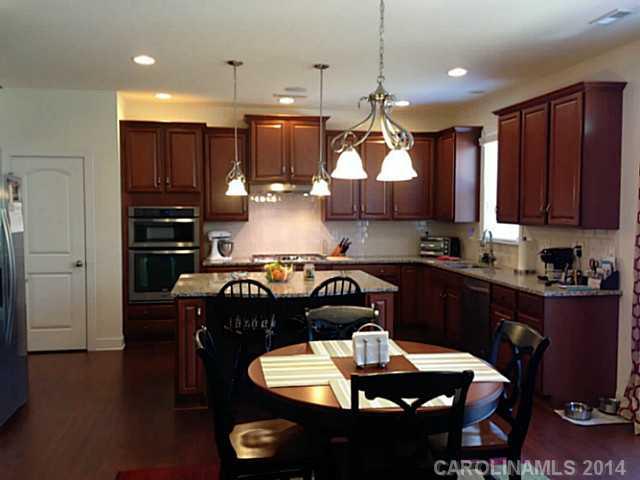 5000 Fallondale Road, Unit 885 Waxhaw, NC 28173 - Photo 8 of 16 a kitchen with stainless steel appliances granite countertop a stove a refrigerator a sink a dining table and chairs with wooden floor
