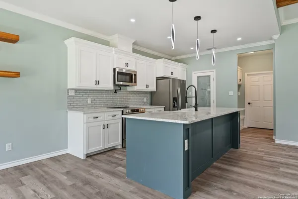 a kitchen with kitchen island granite countertop a sink cabinets and stainless steel appliances