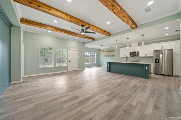 a view of an empty room with kitchen and a window