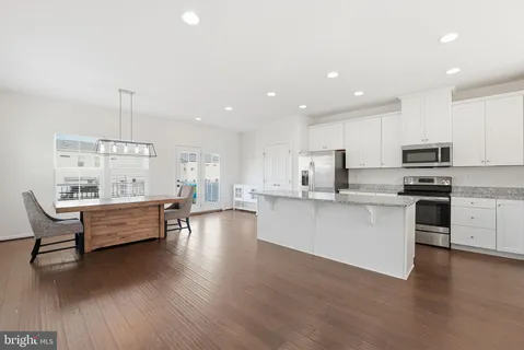 a large white kitchen with white cabinets and wooden floor