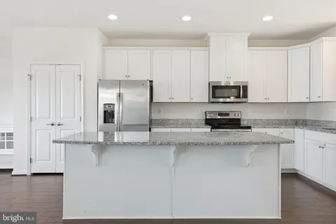 a kitchen with stainless steel appliances granite countertop a refrigerator a stove a sink and white cabinets