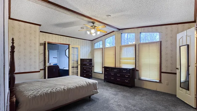 a bedroom with a bed dresser and a large window